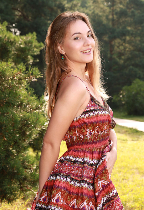 Young happy model Terezza playfully stripping naked outdoors